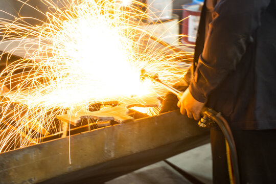 Welding machine with sparks and flashes. Worker and welder welding pipe metal at system assembled in gas and oil refinery plant workshop.