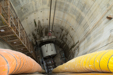 Lift the drill head of tunnel boring machine into the construction shaft using a crane. Engineer...