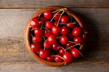Ripe and juicy cherries in wooden bowl on the dark rustic background. Selective focus. Shallow depth of field.