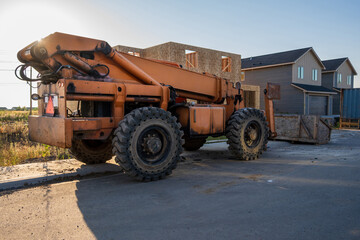 Orange telehandler equipment in front of new residential duplex homes under construction.