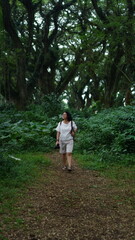 Fototapeta premium A woman walking alone in a small forest is having a backpack and a camera