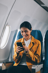 Fototapeta premium Texting on mobile chat app, Thoughtful asian people female person onboard, airplane window, perfectly capture the anticipation and excitement of holiday travel. chinese, japanese people.
