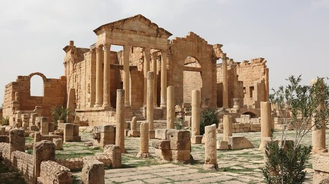Scenic view of ancient Roman forum at Sbeitla archaeological site in Tunisia with majestical ruins of temple dedicated to Capitoline Triad - Jupiter, Juno, and Minerva on spring day