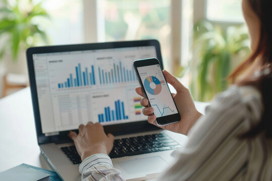 young woman using smartphone and laptop at workplace