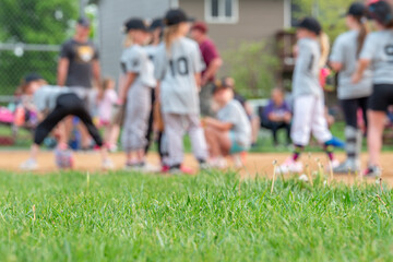 Selective focus on grass with blurred girls softball game in the background