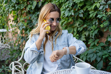 Portrait of cheerful girl typing in mobile while situating at table while listening music in headset. .Lifestyle concept