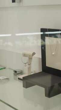Vertical no people close-up of elegant minimalistic set of fine jewellery, earrings and necklace with withe pearl showcased in premium accessory boutique