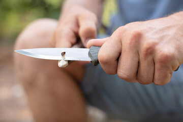 man is sharpening a stick with a knife