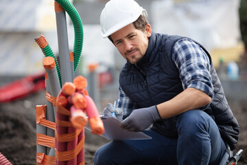 workman inspecting pipe conduits on site
