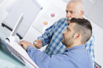 male teacher explaining topic on laptop to student