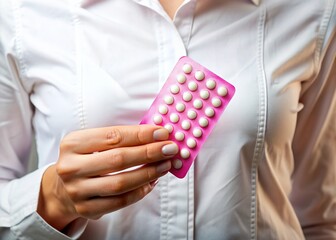 White blouse-draped hand cradles a pink blister pack of hormonal oral contraceptives, symbolizing estrogen and progestin balance in birth control methods for women's reproductive health.
