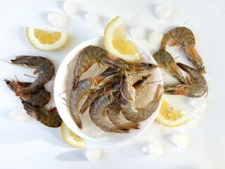 Healthy food. Fresh shrimps with ice and lemon on bowl on white background top view
