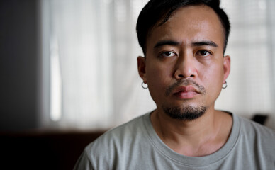 Obraz premium With a goatee and an earring, an adult man poses for a portrait in a studio space. 