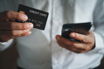 Hand holding credit card and using laptop. Businessman or entrepreneur working from home. Online shopping, e-commerce, internet banking, spending money, work from home concept.
