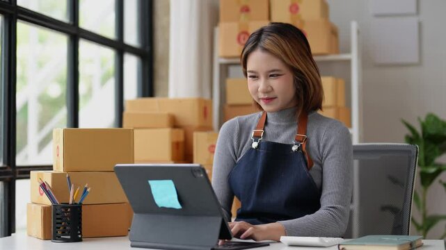 SME entrepreneur Small business entrepreneurs Online selling ideas,Happy Young Asian business owner work on computer and a boxs at home,delivery SME procurement package box deliver to customers.