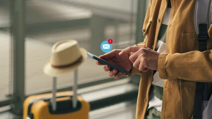 Young male tourist at the airport receives a message from an email on his phone. Concept of receiving a letter by email. - Powered by Adobe