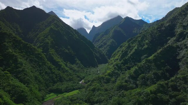 Towering mountain volcano peaks valley rivers Teahupoo Tahiti French Polynesia Moorea Papeete aerial drone stunning island late morning afternoon blue sky daytime sunny clouds scenery forward upwards