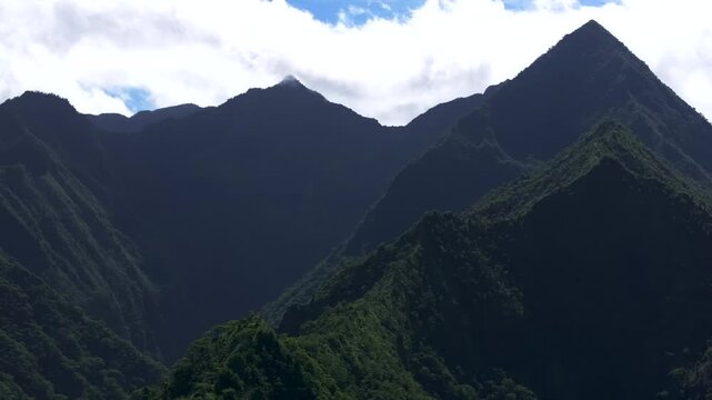 Towering mountain volcano peaks valley Teahupoo Tahiti French Polynesia Moorea Papeete aerial drone parallax late morning afternoon daytime sunny clouds stunning island scenery slowly circle right