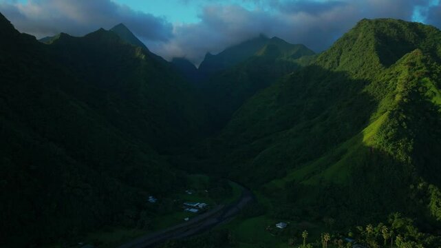 Teahupoo Tahiti French Polynesia aerial drone view sunset light towering mountain peaks valley town villageincredible dark clouds island landscape Moorea Bora Bora Papeete forward pan up