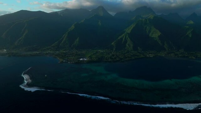 Last light sunset on towering mountain peaks surf reef break channel Teahupoo Wave Tahiti French Polynesia aerial drone view incredible stunning island landscape Moorea Bora Bora Papeete backwards pan
