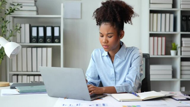 African businesswoman is working on laptop computer doing accounting analysis report for a long time. Feeling stressed Headache with problematic real estate investment information in the office.