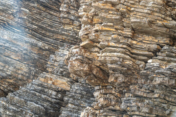 Layered rock texture in Budva, Montenegro. Rugged surface shows various shades of gray and brown