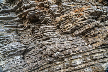 Layered rock texture in Budva, Montenegro. Rugged surface shows various shades of gray and brown