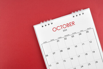 October 2024 desk calendar on red background.