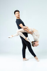 Ballet Dance Concepts. Sportive Couple of Asian Man and Caucasian Woman Performing As Ballet Dancers On Grey in Studio During Suppots As Classical Dance © danmorgan12