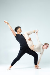 Ballet Dance Ideas and Concepts. Sportive Couple of Asian Man and Caucasian Woman Performing As Ballet Dancers On Grey in Studio During Suppots As Classical Dance © danmorgan12