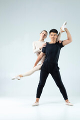Dance Ideas. Sportive Couple of Asian Man and Caucasian Woman Performing As Ballet Dancers On Grey in Studio During Suppots As Classical Dance And Choreography. © danmorgan12