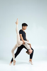 Dance Ideas. Sensual International Sportive Couple of Asian Man and Caucasian Woman Performing As Ballet Dancers On Grey in Studio During Suppots As Classical Dance © danmorgan12