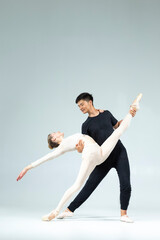 Modern Ballet Ideas. Sensual Passionate Professional International Sportive Couple of Asian Man and Caucasian Woman Performing As Ballet Dancers On Grey in Studio During Suppots As Classical Dance © danmorgan12