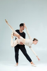 Flexible Passionate Professional International Sportive Couple of Asian Man and Caucasian Woman Performing As Ballet Dancers On Grey in Studio During Suppots As Classical Dance © danmorgan12