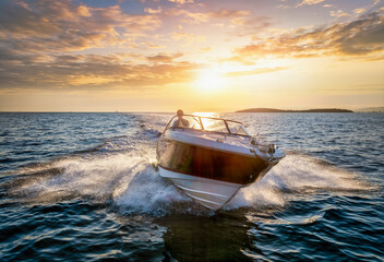 Aerial front view of a sports motor boat cruising with high speed over the blue sea during summer sunset time