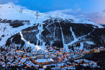Aerial view of snowy ski slopes and Madesimo at night, Lombardy, Italy
