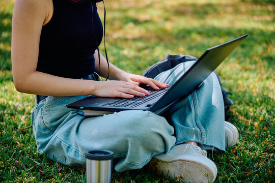 University student typing on laptop outdoors