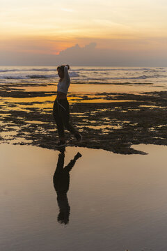 Young woman at sunset on the ocean, on the beach.