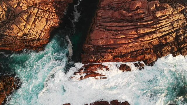 Slow motion aerial of ocean water crashing and flowing into rocks at Canal Rocks, Western Australia