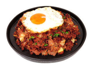 Traditional corned beef hash meal with a fried egg isolated on a white background