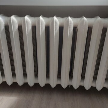 Old painted white iron radiator on a white wall