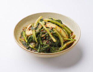 Close-up of young radish kimchi with leaves and chili powder on dish and white floor, South Korea
