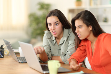 Two upset tele workers working checking laptop at home
