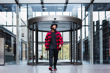 Positive African American guy near glass building entrance