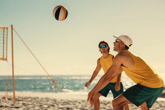 Pro volleyball players engage in intense beach match at sunset - Powered by Adobe
