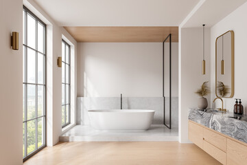 Cozy hotel bathroom interior with tub, sink and accessories, panoramic window