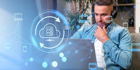 Man in headphones using laptop, cloud service hologram and system backup