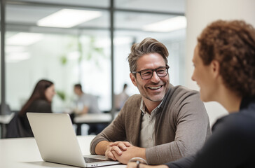 Obraz premium Smiling Businessman Engaging In Friendly Conversation With Colleague In Bright Office Space