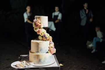 a beautiful wedding cake near the wedding arch in the evening