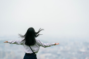 高台で空に向かって両手を広げる女性, 乱れている髪の毛